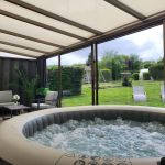 V&eacute;randa avec salon de d&eacute;tente et spa gonflable avec vue sur le jardin